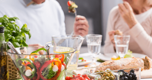 A man and woman sitting down to eat at a table set with a variety of dishes.